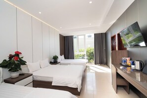 Habitación de hotel con dos camas, televisor, escritorio y ventana con cortinas.