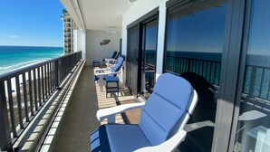 A balcony with two blue chairs, a white ceiling fan, and a view of the ocean. - Breakers East 1202- Gulf Front Spacious 2 BR/2BA Beach setup included (Destin)
