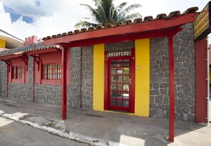 A building with a reception area, stone walls, and a red door. - Pousada dos Gravatais (Marataizes)