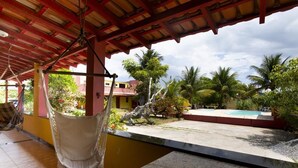 Un’area esterna coperta con un’amaca, una piscina e palme.