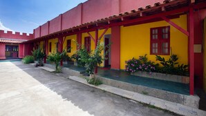 Un edificio con pareti esterne gialle e rosse, un tetto in tegole e un cortile lastricato.