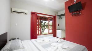 Una camera d'albergo con un letto, una TV a muro e un condizionatore.