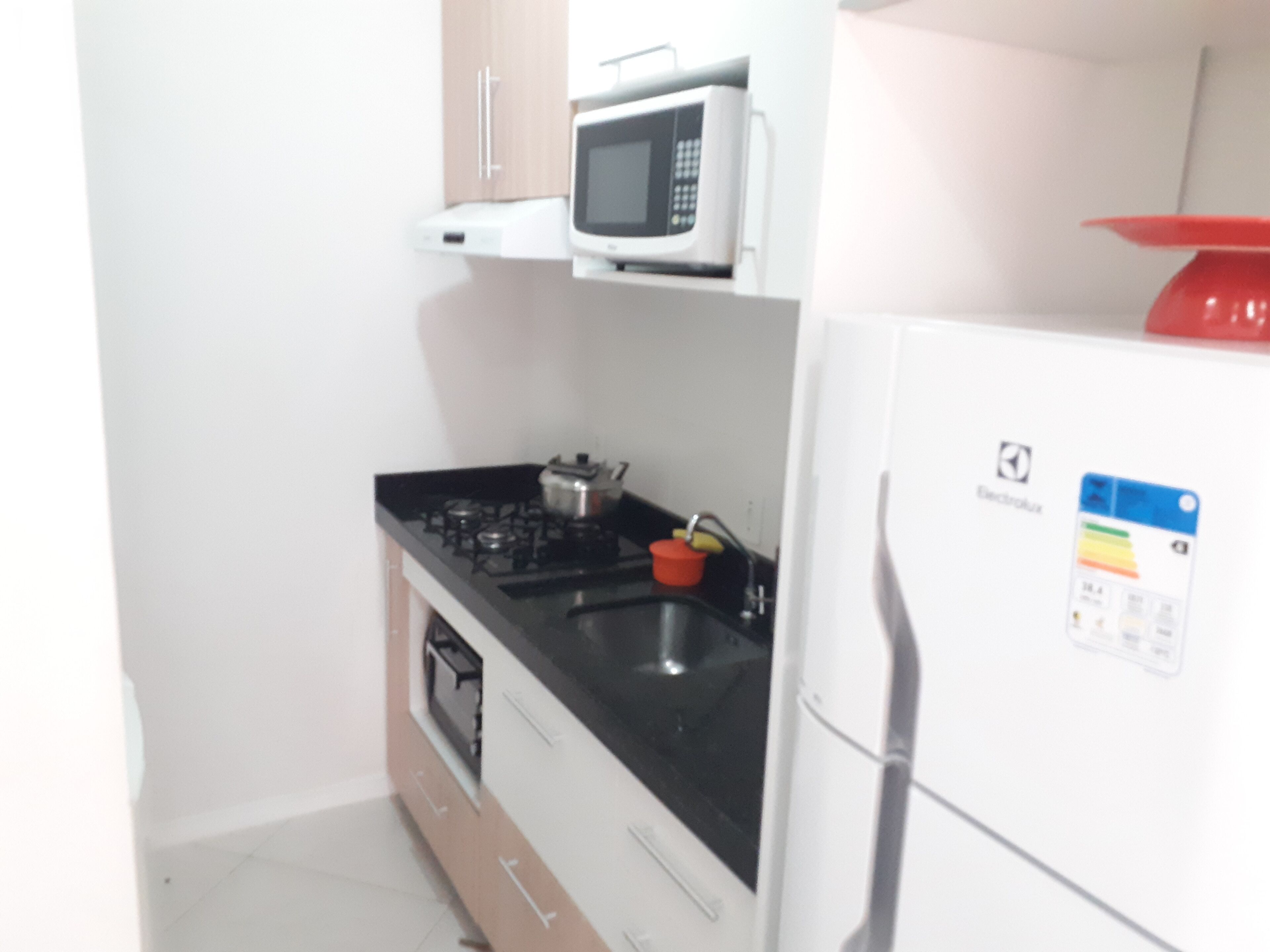 A compact kitchen with a microwave, stove, and refrigerator.