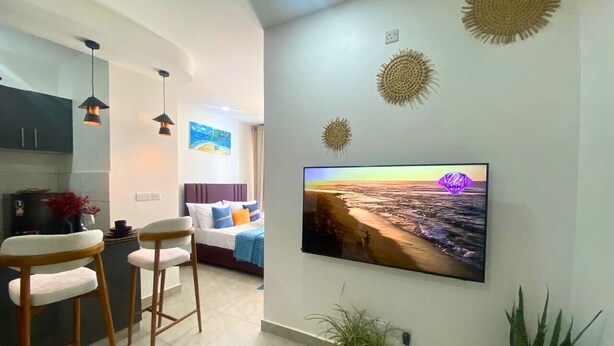 Ein modernes Wohnzimmer mit Flachbildfernseher, Barhocker, einer Couch und dekorativen Wandbildern.