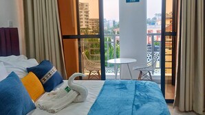 Ein Hotelzimmer mit einem Bett, einem schwanenförmigen Handtuch, einem Balkon mit Tisch und Stühlen und einem Schild mit dem Hinweis auf Vitamin-Meer-Bedarf.