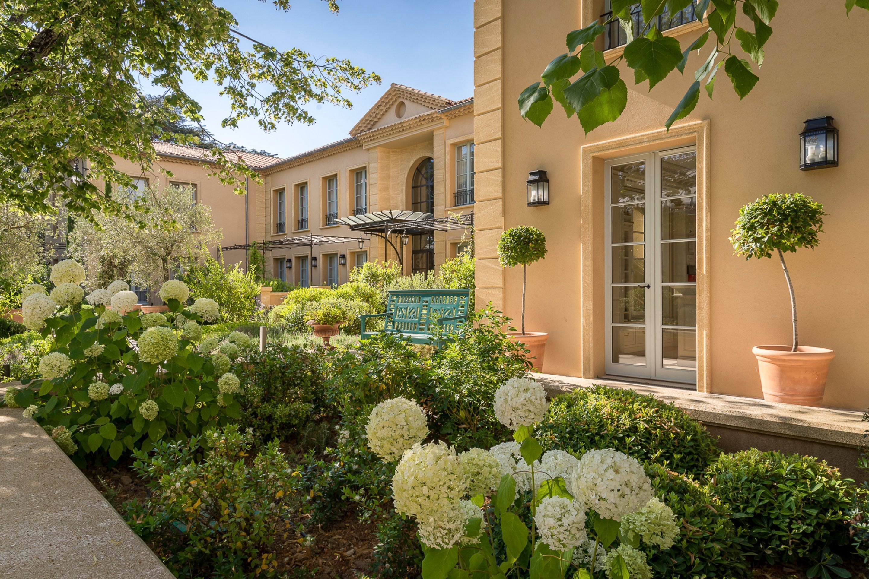 A building with a garden, a bench, and a potted plant.