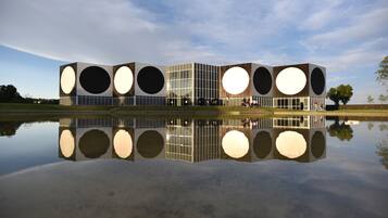 Un edificio moderno con grandes ventanales circulares y su reflejo en el agua.