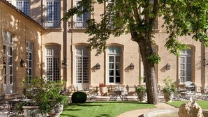 A courtyard with a fountain, outdoor seating, and a building with large windows and a tree. - Villa Saint-Ange Hôtel & Spa (Aix-en-Provence)