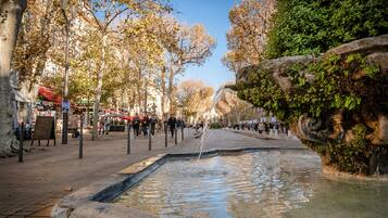 Una plaza pública con una fuente, árboles y un paseo peatonal.