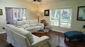 A living room with a beige sofa, a glass coffee table, and a blue armchair. - Lakefront VERY PRIVATE Guest House with Gorgeous Lake Views!  2-Bed, 2-Bath (Brandon)