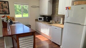 A modern kitchen with white cabinets, a wooden countertop, a white refrigerator, and a window providing natural light. - Lakefront VERY PRIVATE Guest House with Gorgeous Lake Views!  2-Bed, 2-Bath (Brandon)