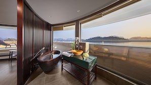 Ein modernes Badezimmer mit einer großzügigen Badewanne, einem Holzbadschränken und Meerblick.