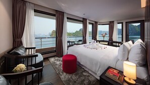 Ein modernes Hotelzimmer mit einem großen Bett, einer Sitzecke und einem Balkon mit Meerblick.
