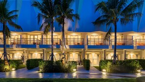 A multi-story hotel with balconies, palm trees, and well-lit pathways. - La Vida Samui (Koh Samui)