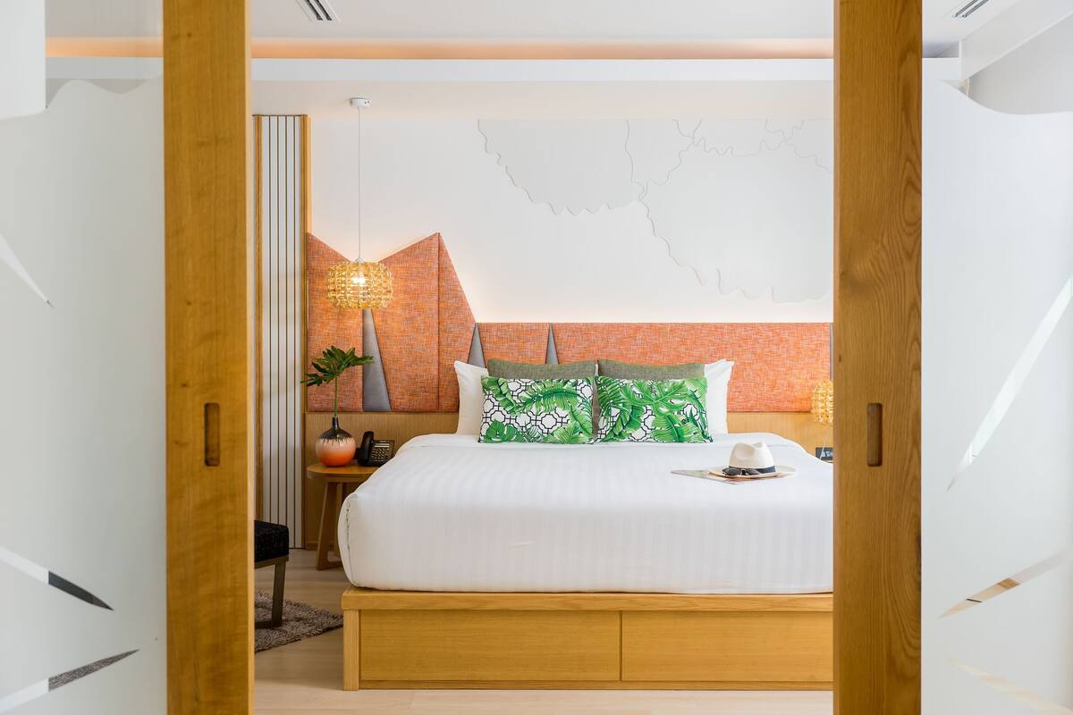 A modern bedroom with a large bed, wooden headboard, and a decorative wall with a geometric pattern.