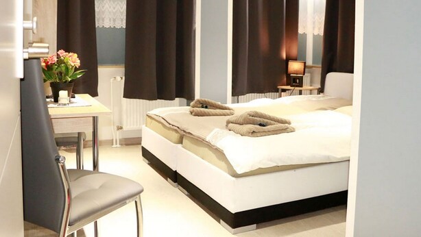 Una habitación de hotel con cama, escritorio, silla y mesita de noche con lámpara.