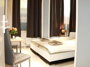 Una habitación de hotel con cama, escritorio, silla y mesita de noche con lámpara.