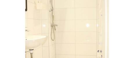 A small, clean bathroom with a white sink, toilet, and shower.