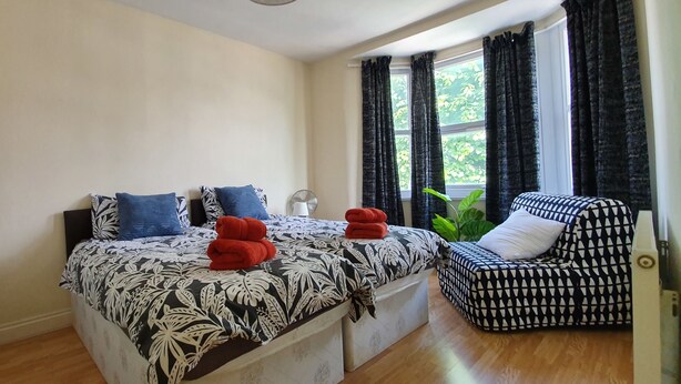 Une chambre à coucher avec un lit, une chaise et une fenêtre avec des rideaux.