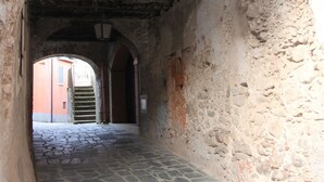 An arched stone passageway with a tiled floor and a metal grate at the end. - Le Vie Mediterranee (Torre di Ruggiero)
