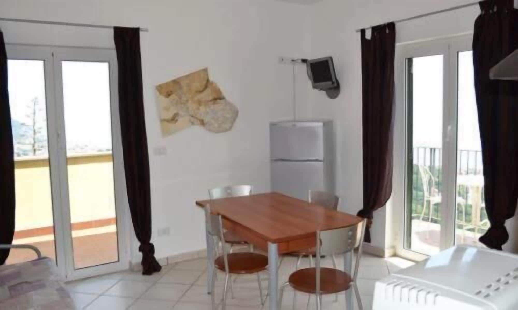 A room with a wooden table and chairs, a white radiator, a stone wall decoration, and a sliding glass door leading to an outdoor area.