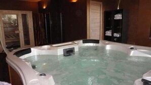 A hot tub in a room with wooden walls and a glass door.