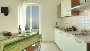 A kitchen with a dining table set for two, a window with a view, and a balcony.