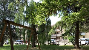 A park with a wooden swing set, a picnic table, and a fence. - A very large holiday home in Valpolicella, suitable for several families, (Arbizzano-Santa Maria)