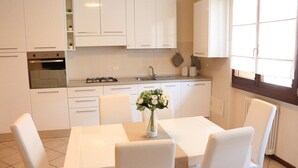A modern kitchen with white cabinetry, a central island with chairs, and a vase of flowers. - A very large holiday home in Valpolicella, suitable for several families, (Arbizzano-Santa Maria)