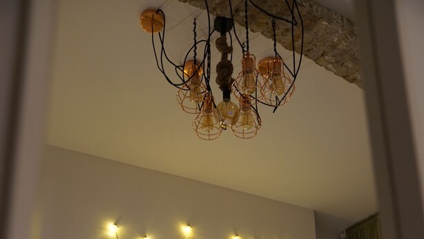A bedroom with a quilted headboard, a bed with white linens, and a wall-mounted light fixture with multiple bulbs. - 364.Berlin (Berlin)