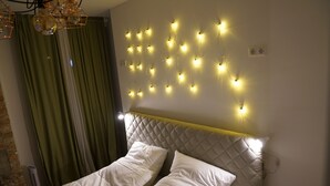 A bedroom with a quilted headboard, a bed with white bedding, and string lights on the wall. - 364.Berlin (Berlin)
