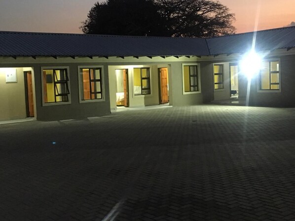 A building with multiple rooms, each with a door and windows. The building has a flat roof and is surrounded by a paved area. - Elson Lodge (Alberton)
