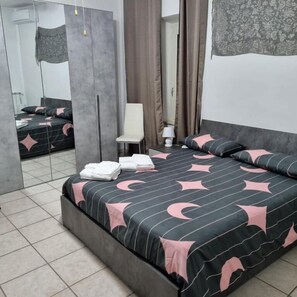 A modern bedroom with a large bed, a chair, a mirror, and a wardrobe.