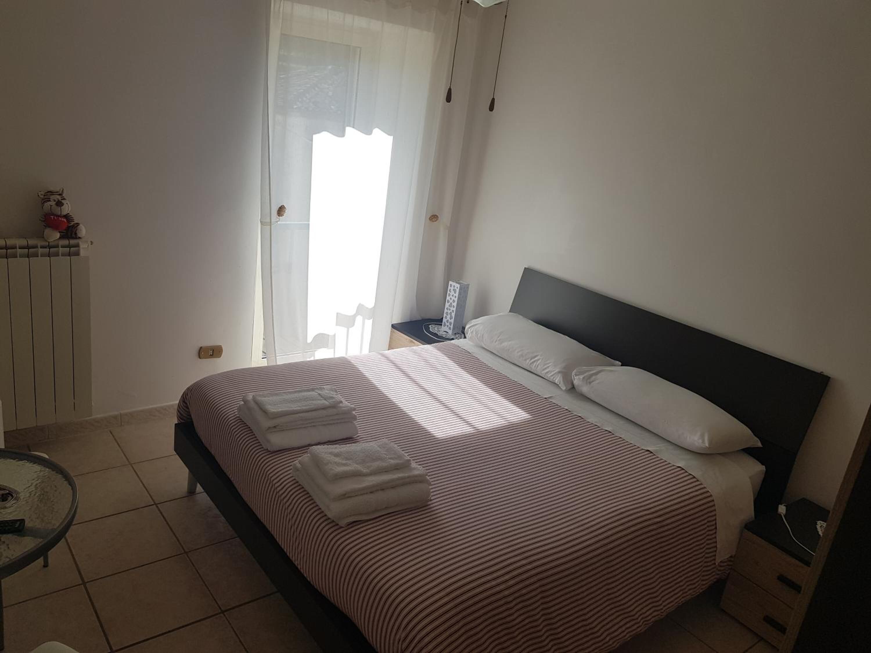 A bedroom with a bed, bedside table, and a chair.