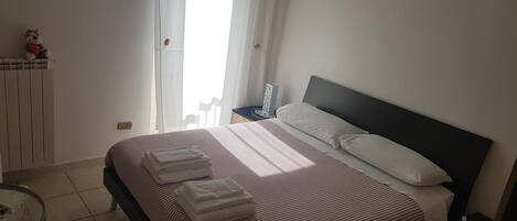 A bedroom with a bed, bedside table, and a chair.