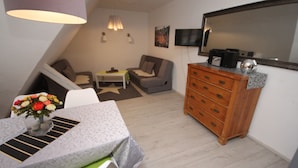 Uma sala de estar pequena e moderna, com uma mesa de jantar, sofá e um aparador de madeira.