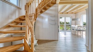 Una escalera de madera que lleva a un balcón con comedor.