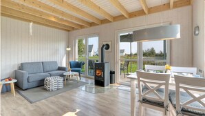 Una sala de estar acogedora con un sofá gris, un sillón azul y un techo de madera.