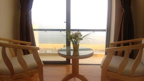 A room with a balcony, two wooden chairs, a small round table, and a potted plant. - Galaxy Hotel (Quy Nhon)
