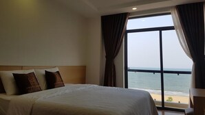 A hotel room with a large bed, a view of the sea, and a balcony with curtains. - Galaxy Hotel (Quy Nhon)