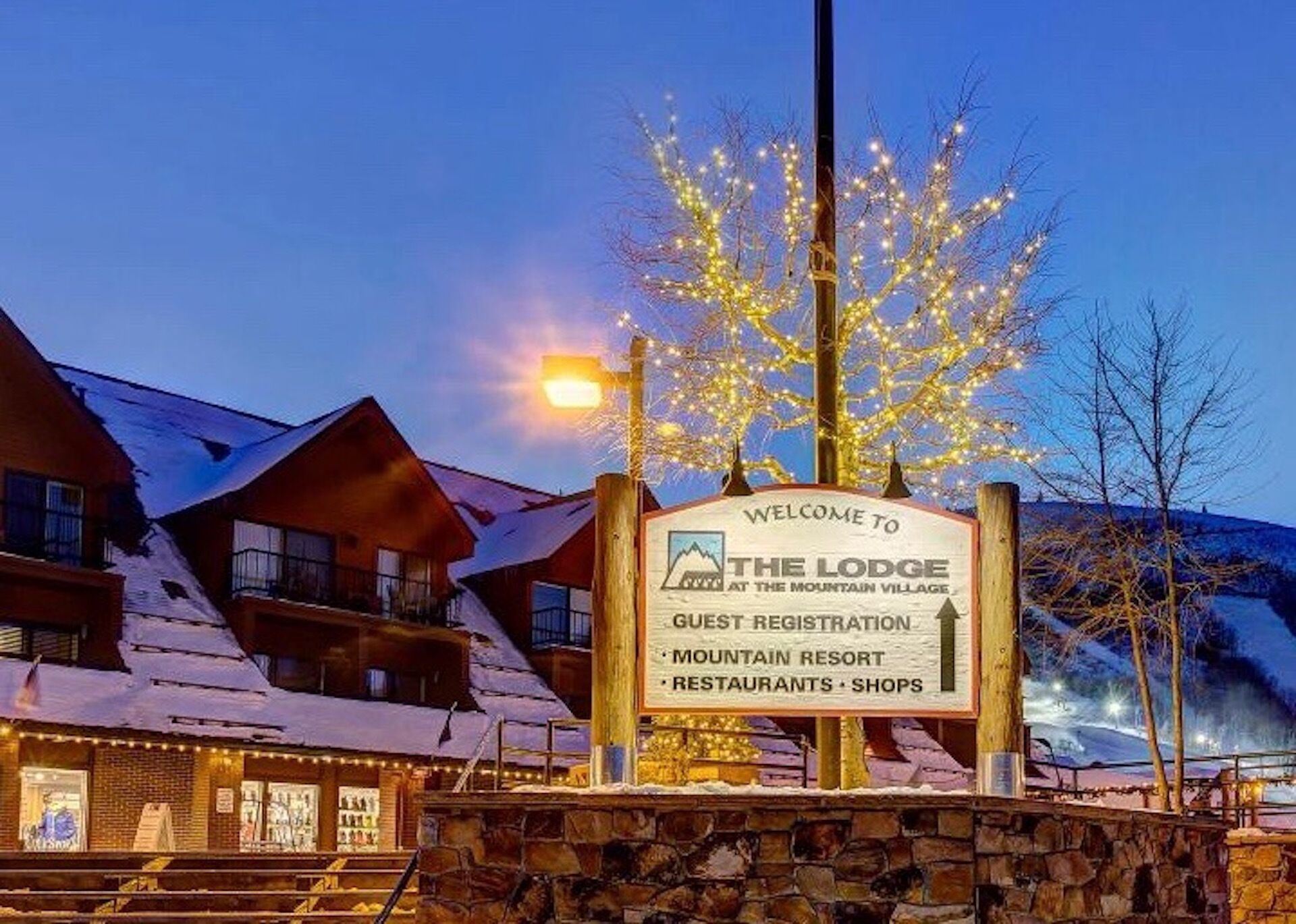 A sign for The Lodge at the Mountain Village with a mountain backdrop.