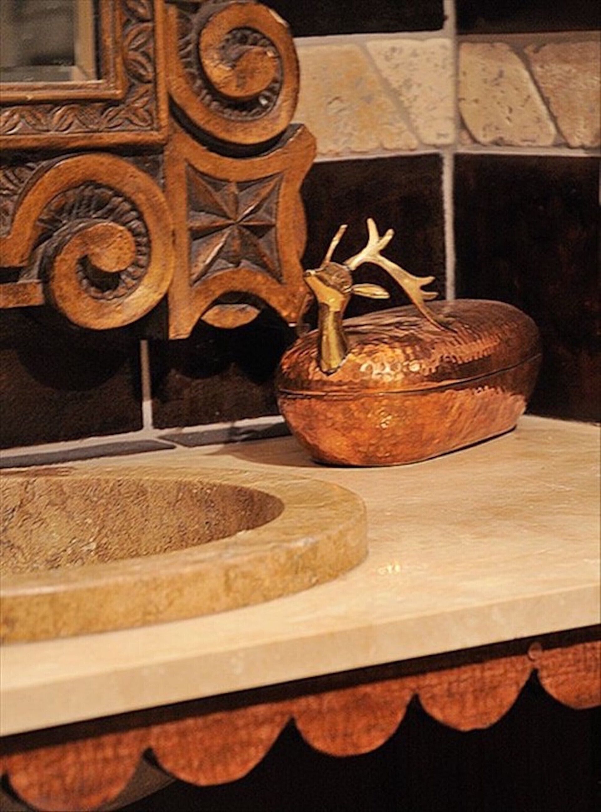 A rustic wooden bowl with a carved deer head on a countertop.
