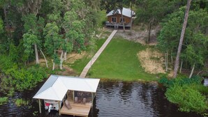 Ein Haus auf Stelzen an einem See mit einem Steg und einer überdachten Sitzterrasse.
