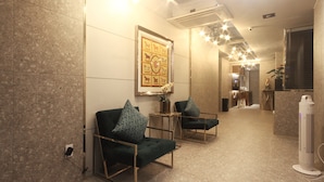 A hotel lobby with two green armchairs, a framed artwork on the wall, and a standing fan. - Browndot Hotel - Seomyeon 1 (Busan)