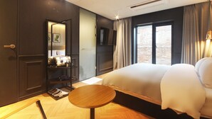 A hotel room with a large bed, a small round table, a wardrobe, a mirror, and a window with curtains. - Browndot Hotel - Seomyeon 1 (Busan)