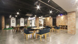 A modern indoor space with a dining area featuring wooden tables and chairs, a brick accent wall, and a ceiling with exposed pipes. - Browndot Hotel - Seomyeon 1 (Busan)