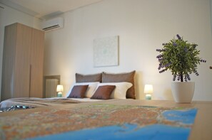 A hotel room with a bed, a map on the table, a potted plant, and a wall-mounted air conditioner. - Bari Rooms Central Station (Bari)