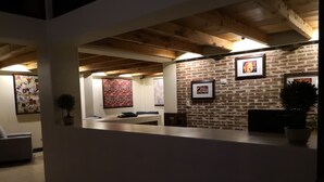 Zona de recepción con pared de ladrillo, obras de arte enmarcadas y mostrador de recepción.