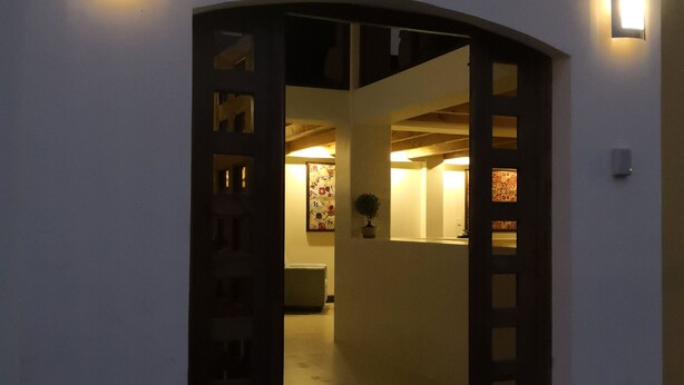 Una entrada de edificio con un arco oscuro y dos apliques de pared iluminados.