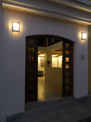 A building entrance with a dark archway and two illuminated wall sconces. - Hotel Mezzanine (San Marcos)